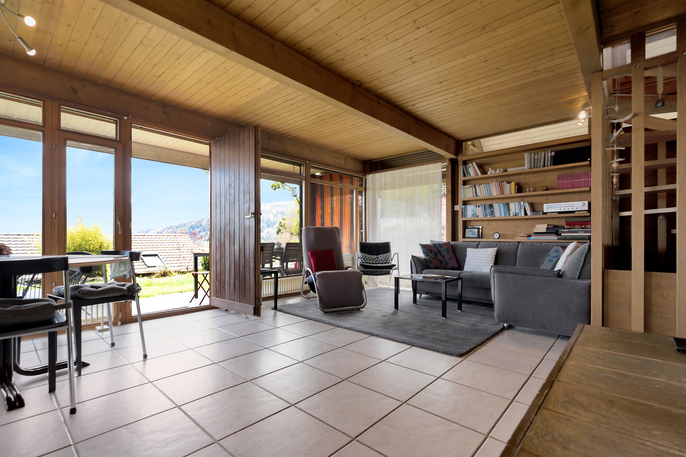 Wohnbereich mit bodentiefen Fenstern und Ausgang zum Gartenbereich mit Sitzplatz