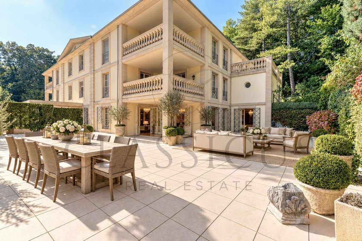 Grande terrasse avec espace repas et détente entourée de verdure.
