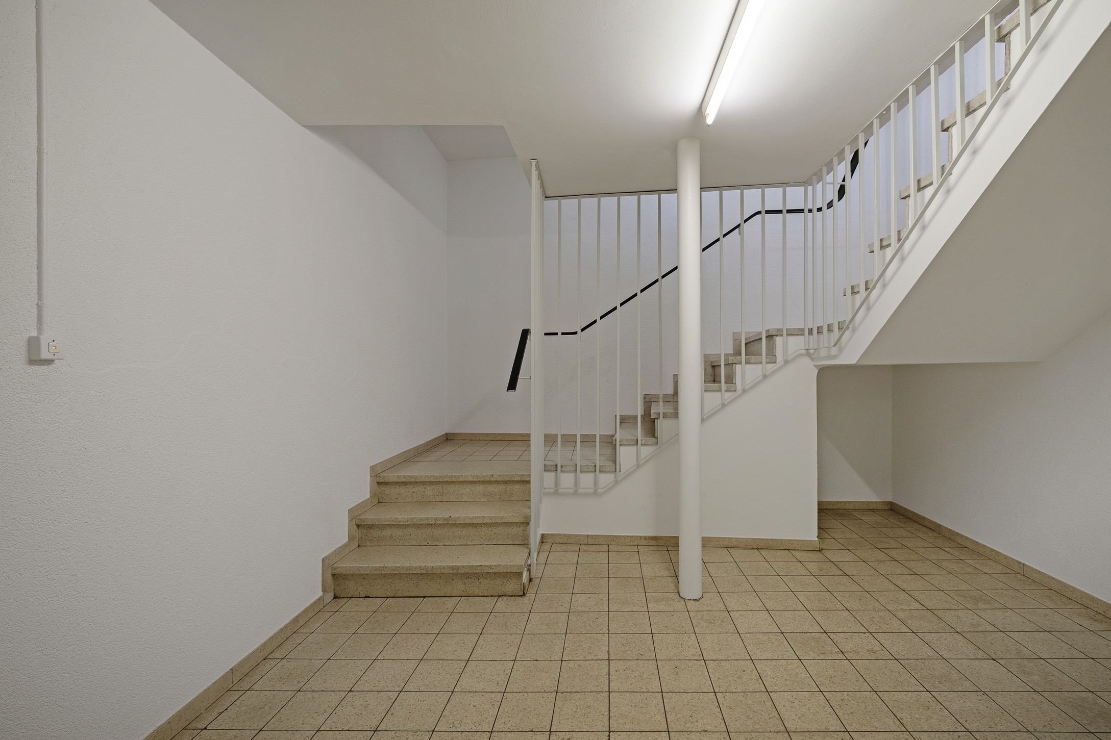 a room with white walls and a staircase leading to the second floor