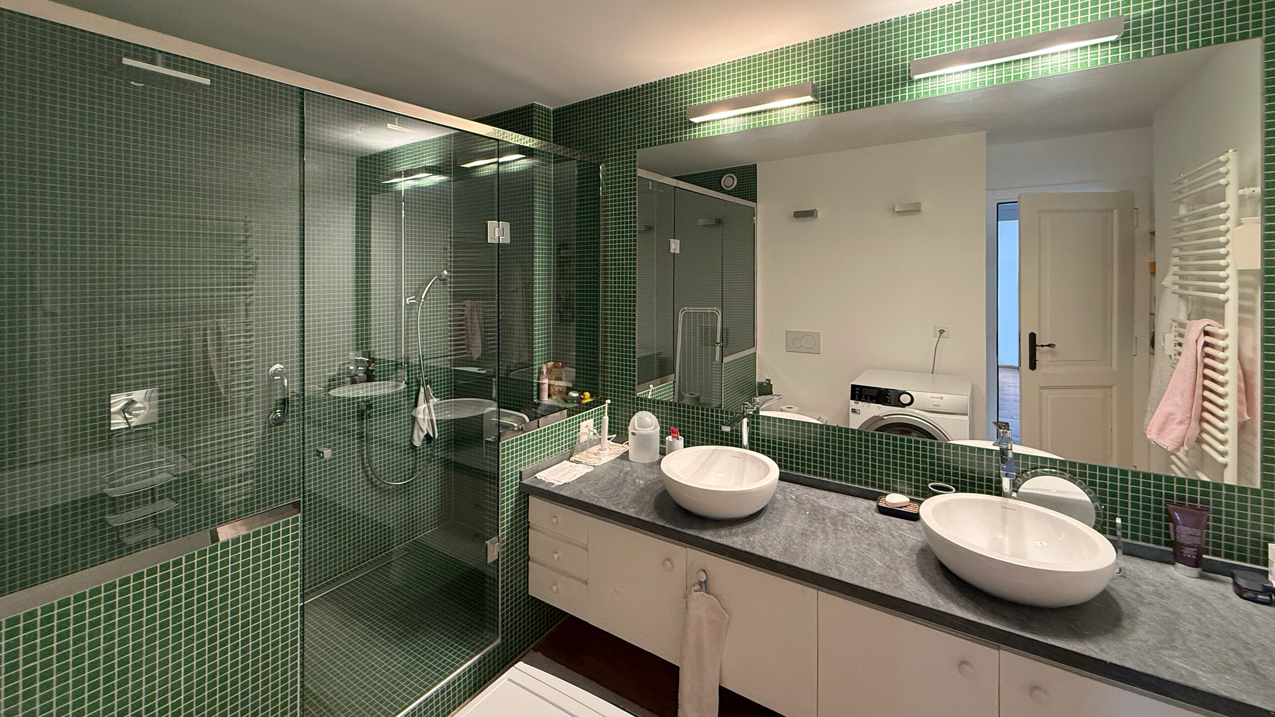 Grande salle de douche avec WC, deux lavabos et buidanderie