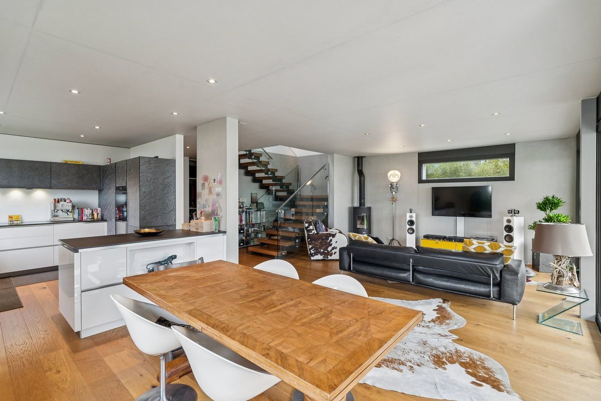 Espace ouvert avec cuisine, salon et escalier moderne.