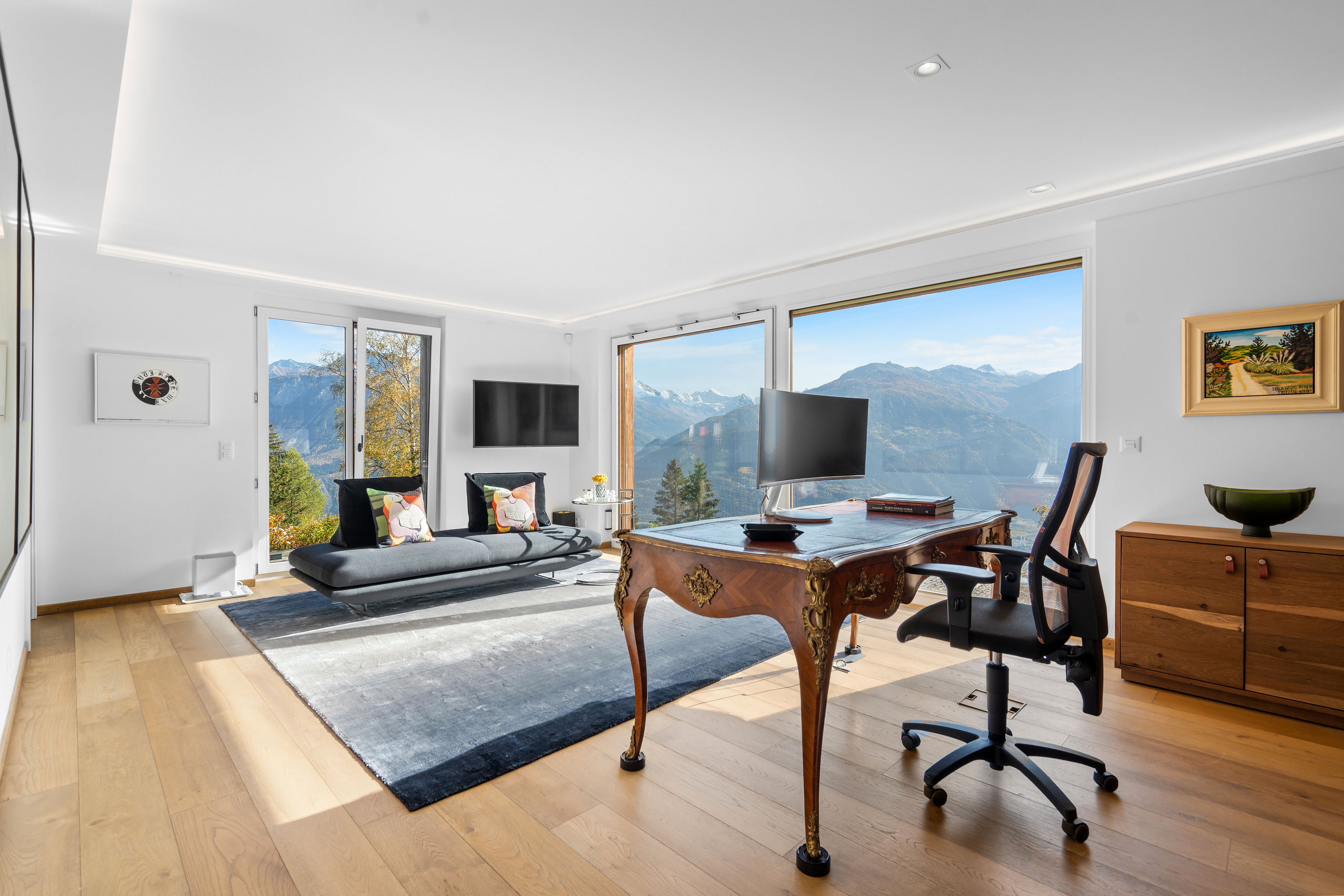 a modern home office with a large window overlooking the mountains and a living room with modern furniture