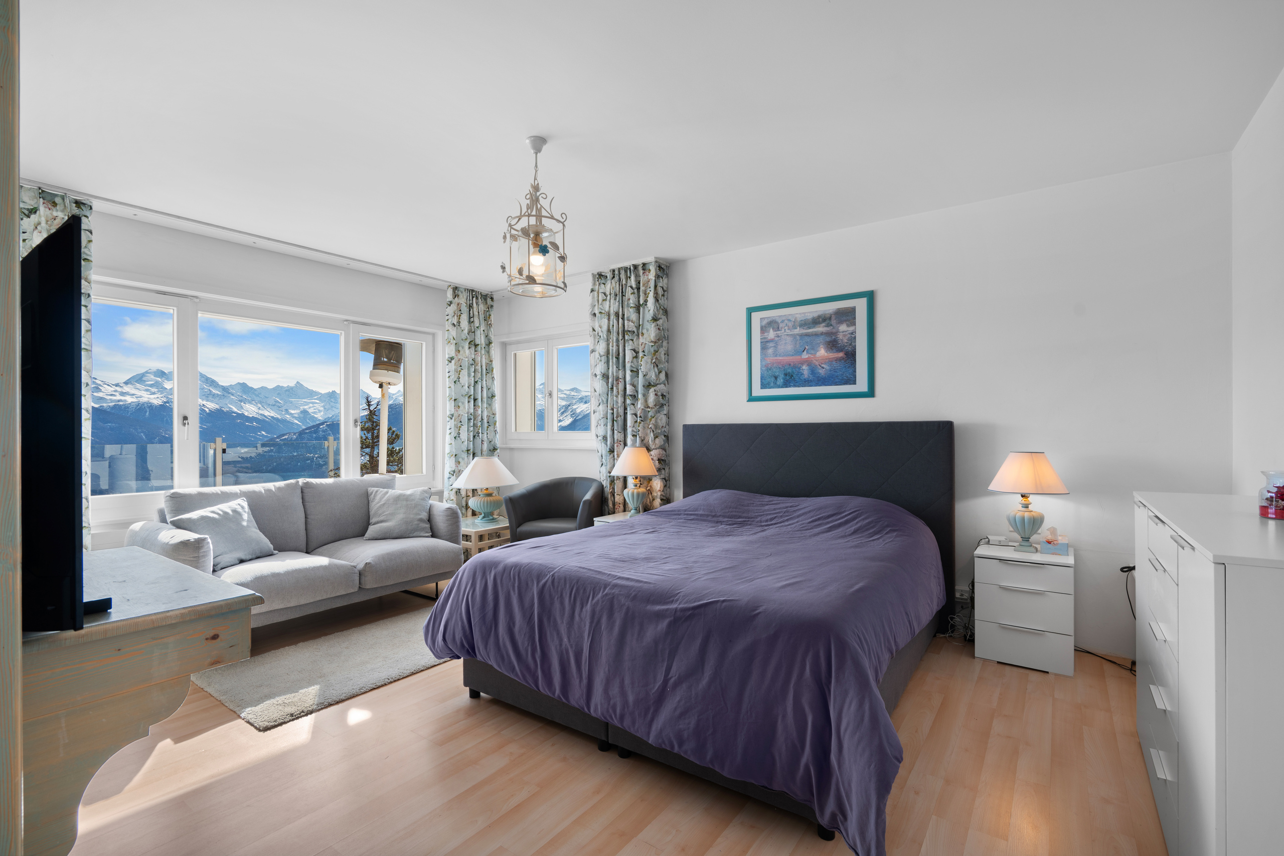 une chambre avec une grande fenêtre donnant sur les montagnes et un lit violet