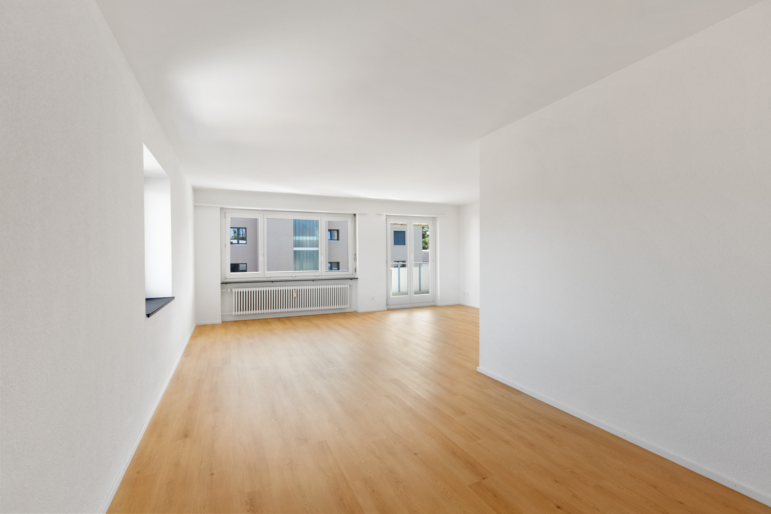 Grosszügiger und heller Wohnbereich mit direktem Zugang zum Balkon.