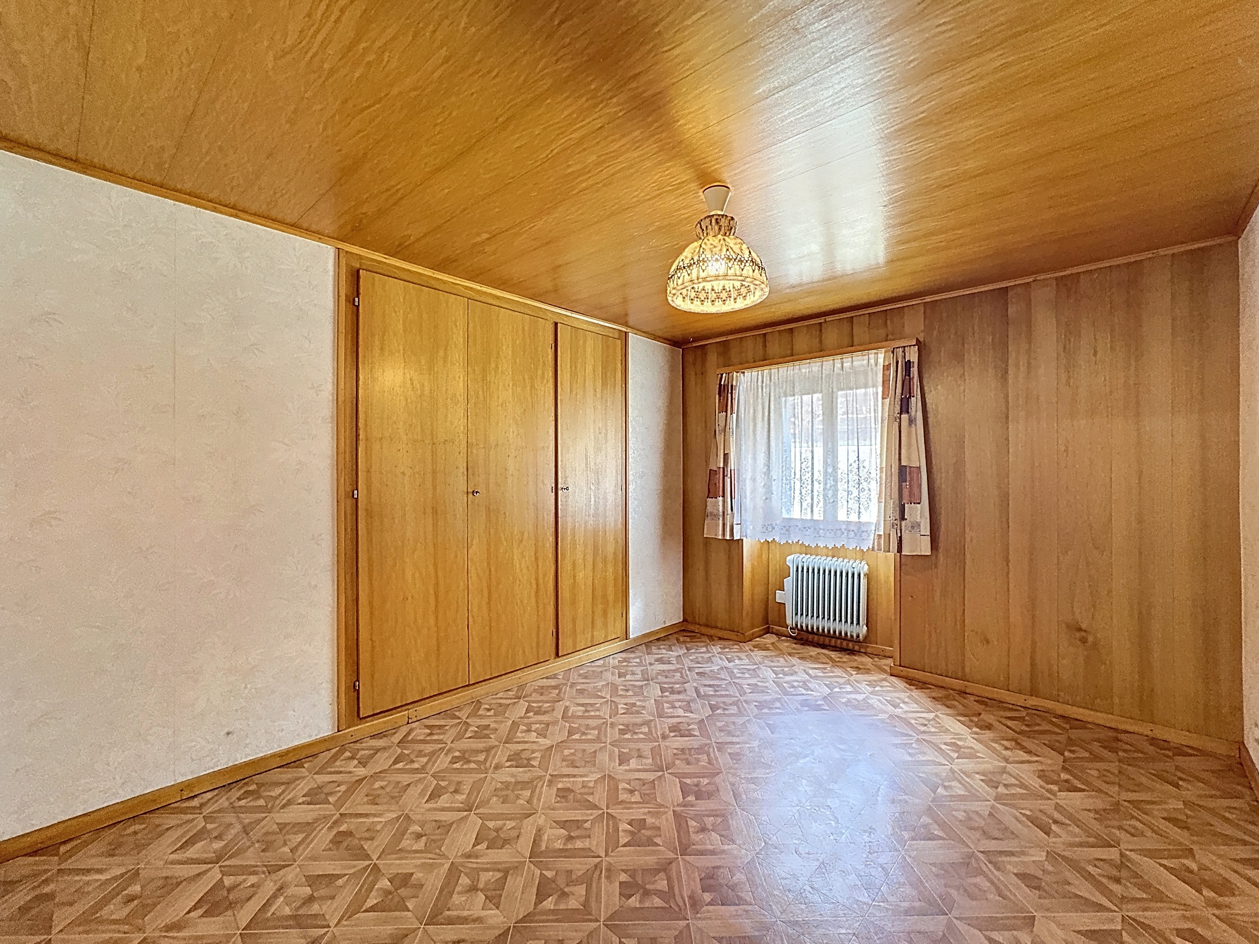 une pièce vide avec des sols et des murs en bois et une grande fenêtre