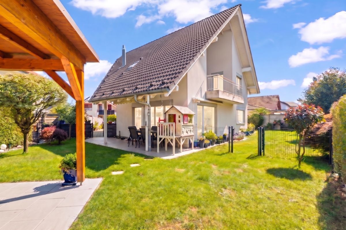 Gepflegter Garten mit überdachtem Sitzbereich und moderner Fassade. Gepflegter Garten mit überdachtem Sitzbereich und moderner Fassade.