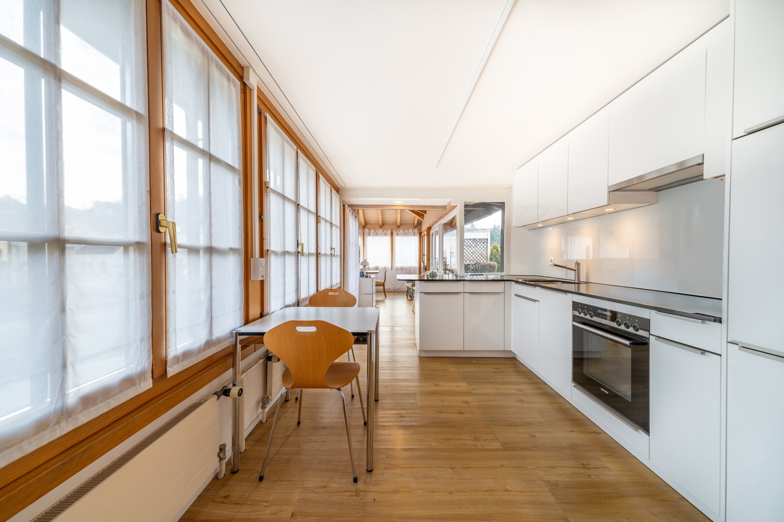 Moderne, weiss gehaltene Küche mit Granitabdeckung und hochwertigen Geräten.