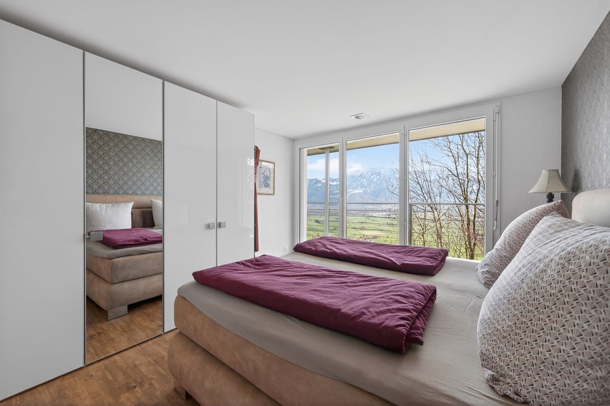 Geräumiges Schlafzimmer mit Panoramafenster und Alpensicht