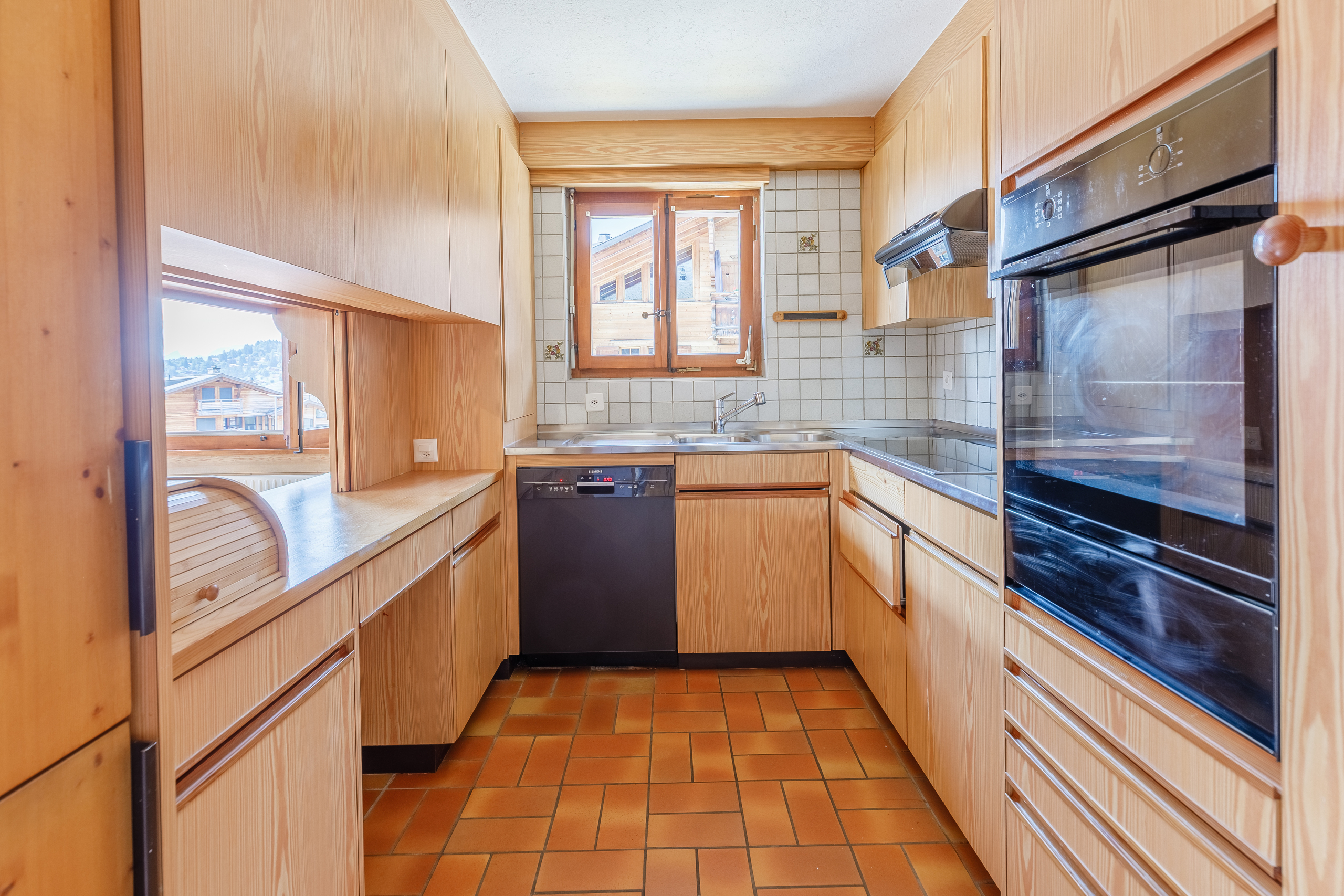 une cuisine équipée d'une cuisinière, d'un four, d'un lave-vaisselle, d'un évier et d'armoires en bois