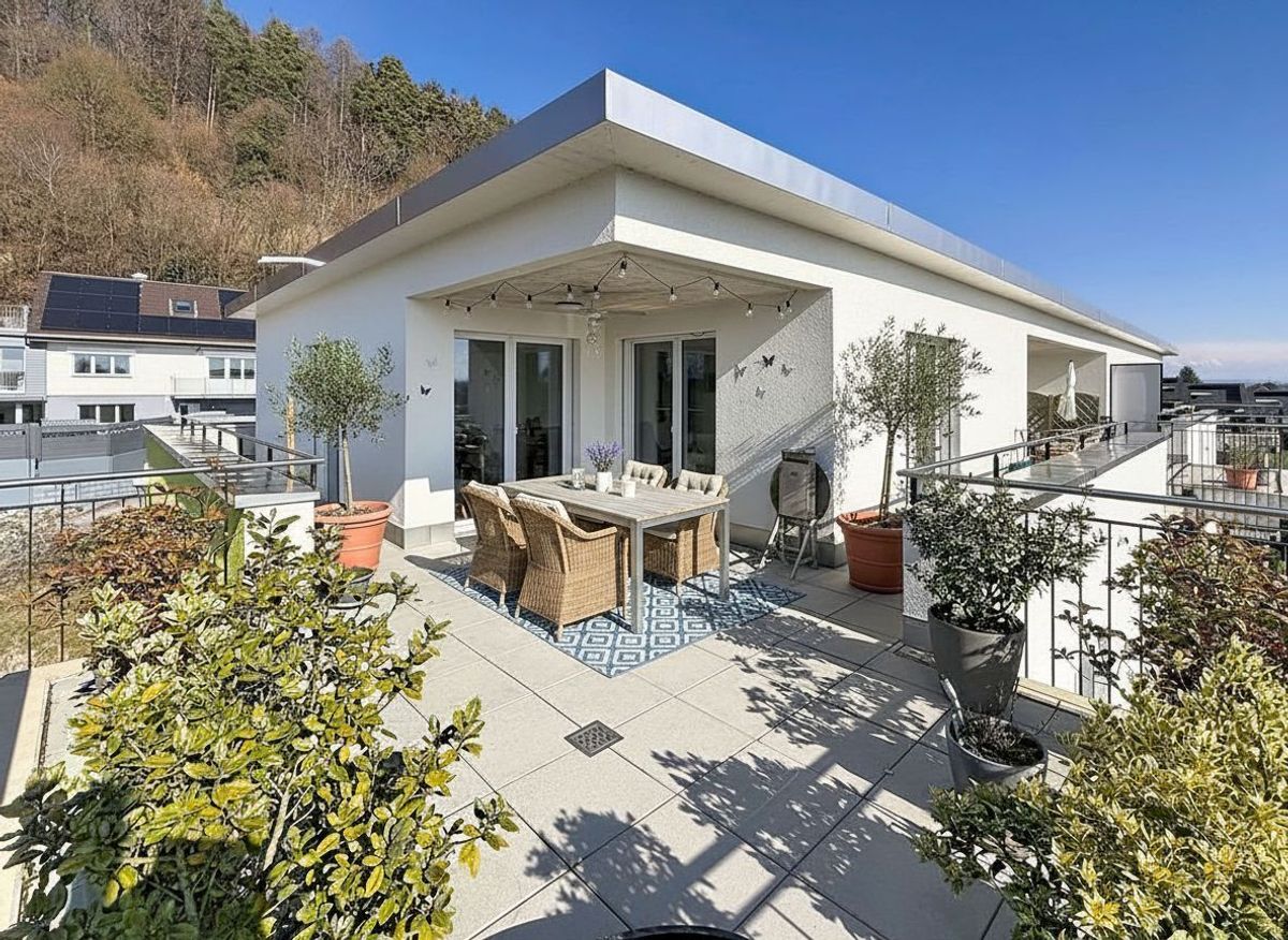 Spacieuse terrasse avec mobiliers et plantes en pot.