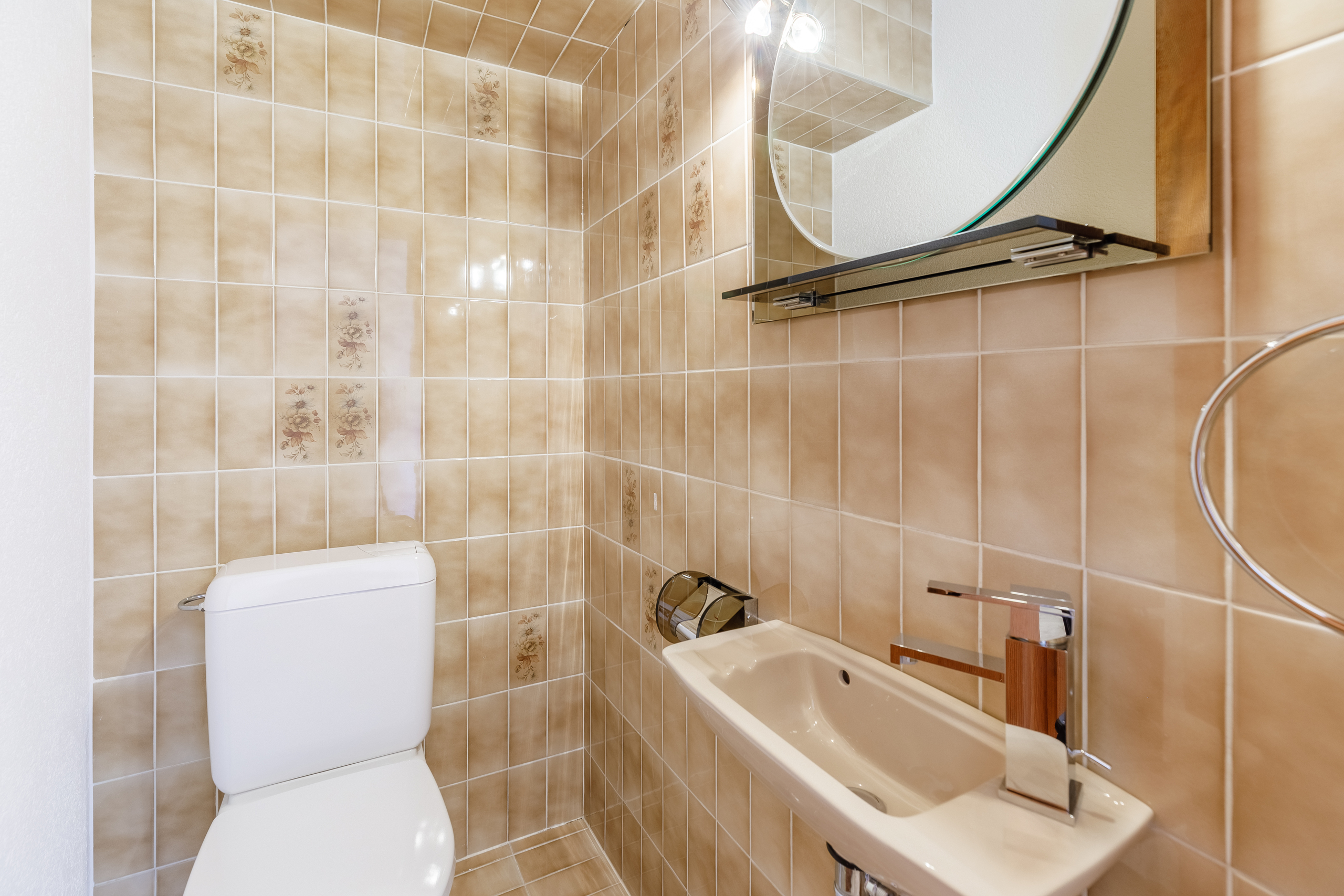 une salle de bains avec des toilettes blanches, un lavabo et un miroir au mur