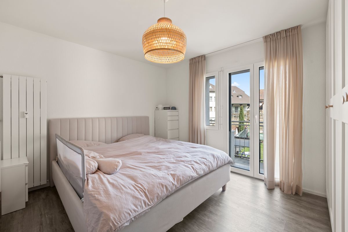 Helles Schlafzimmer mit Zugang zum Balkon und großer Fensterfront.