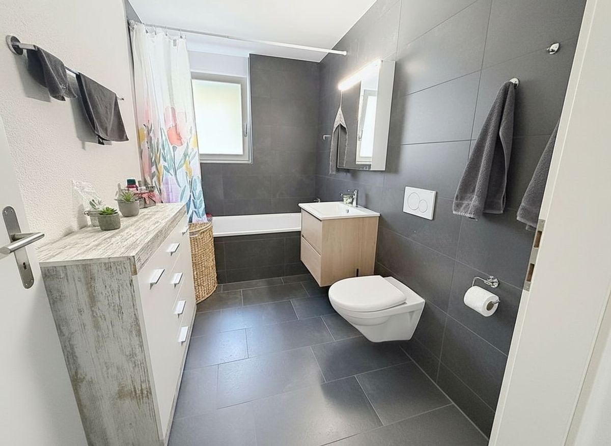 Salle de bain avec baignoire et carrelage foncé.