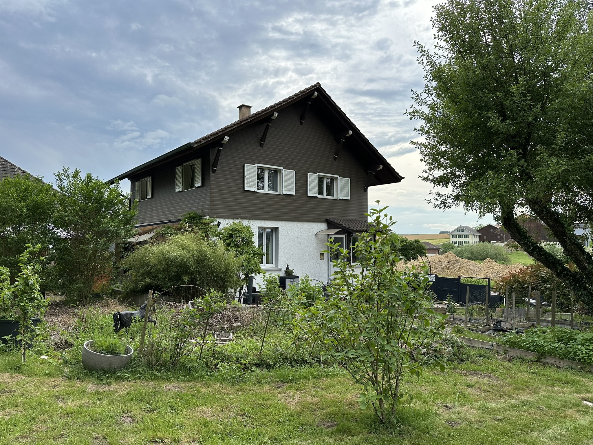 une maison avec un jardin et des arbres devant elle