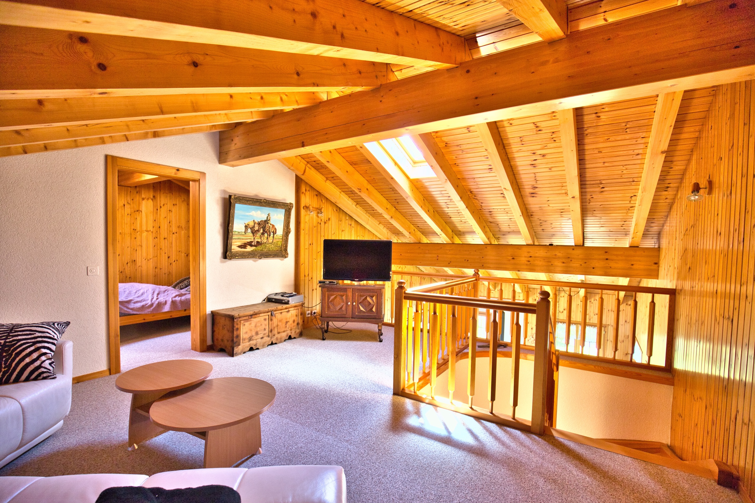 une grande pièce avec un plafond en bois, un canapé, une table et une télévision une grande pièce avec un plafond en bois, un canapé, une table et une télévision