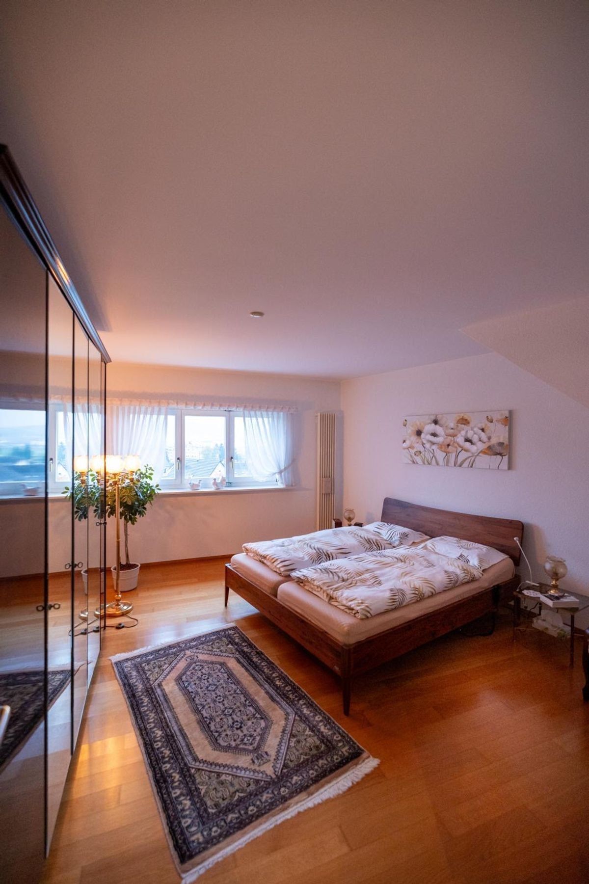 Gemütliches Schlafzimmer mit großem Fenster und Holzfußboden.