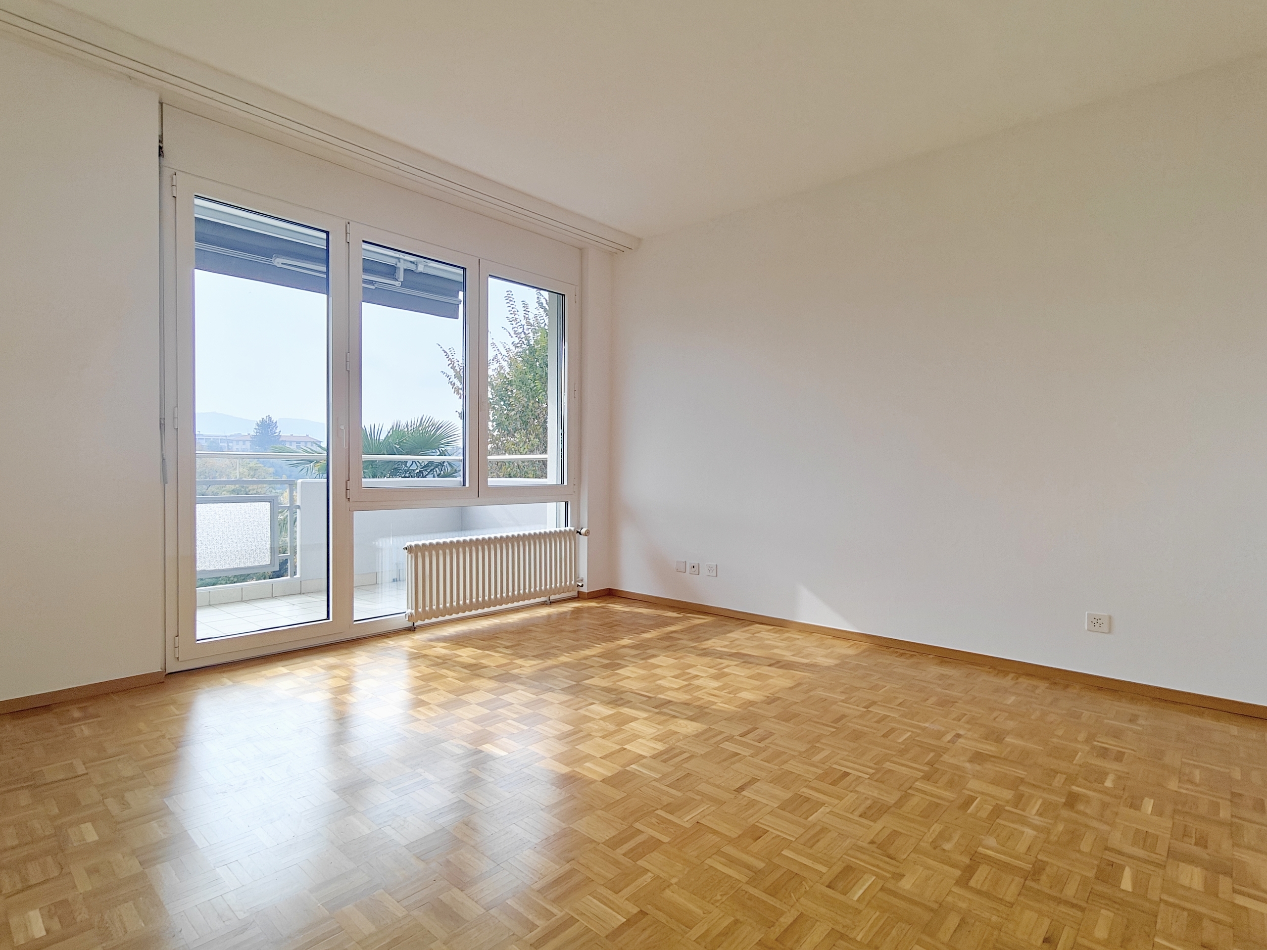 an empty room with wooden floors and a large window overlooking a balcony an empty room with wooden floors and a large window overlooking a balcony