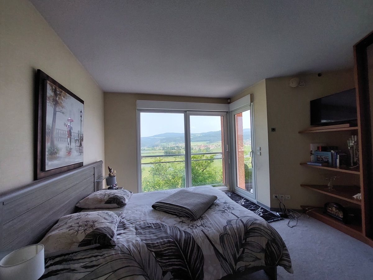 Chambre avec vue sur la campagne par de grandes fenêtres.
