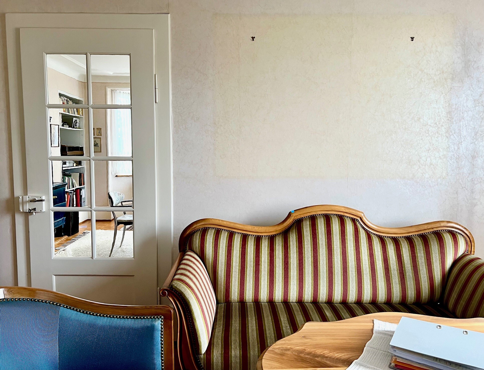 a living room with a striped couch and a table and a door