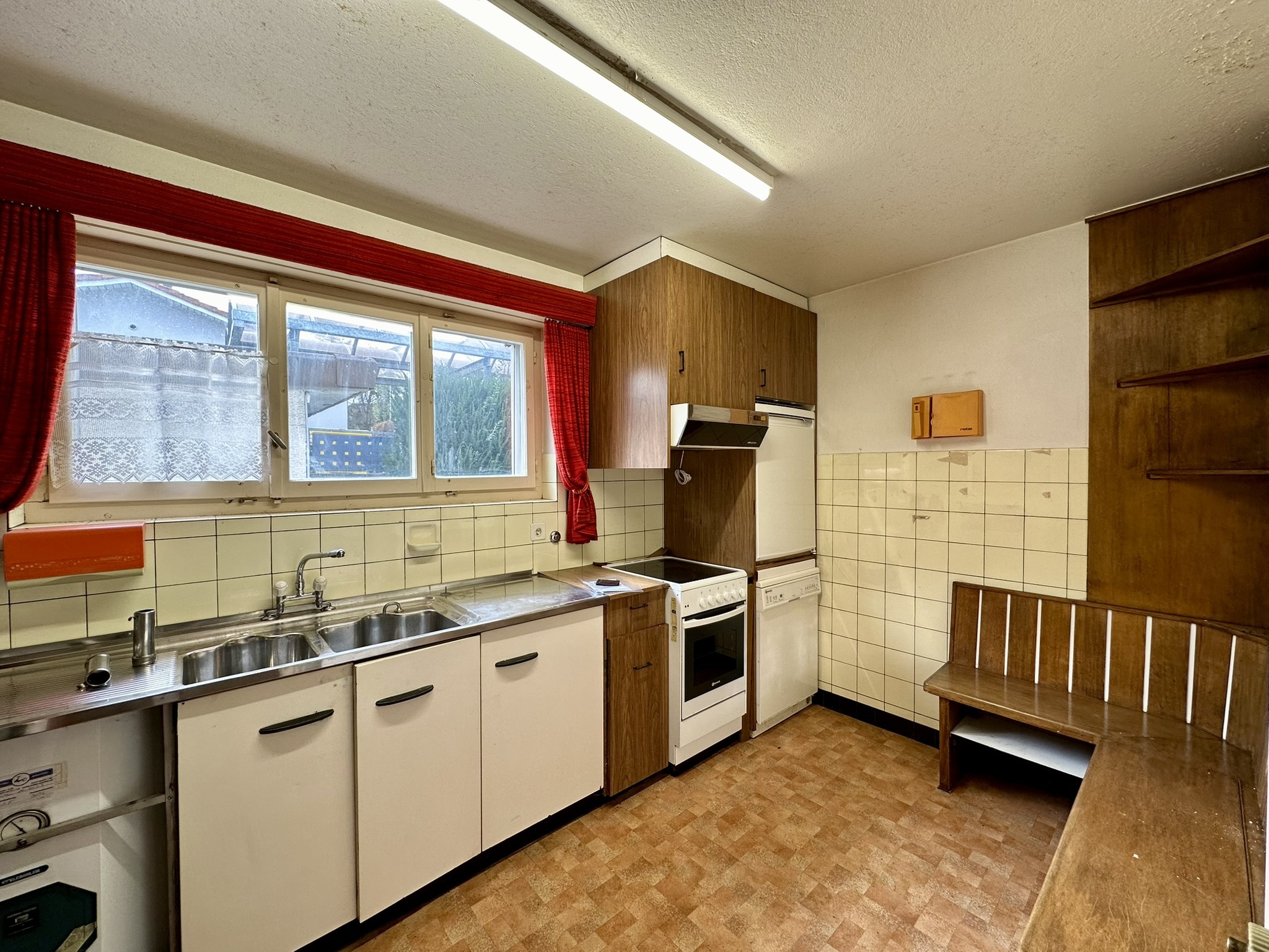 une cuisine avec des armoires en bois, un évier, une cuisinière et une grande fenêtre une cuisine avec des armoires en bois, un évier, une cuisinière et une grande fenêtre