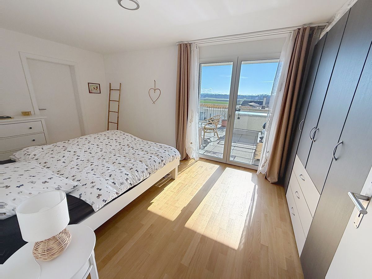 Chambre donnant sur une terrasse avec penderie et parquet en bois.