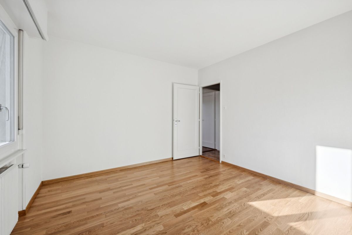 Chambre lumineuse avec parquet et fenêtre.
