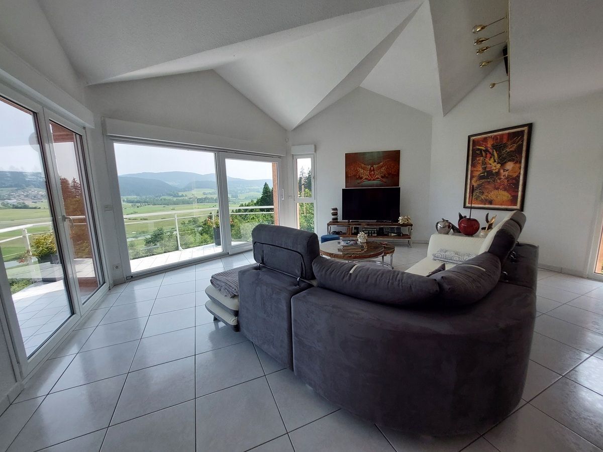 Salon avec vue panoramique et canapé moderne.