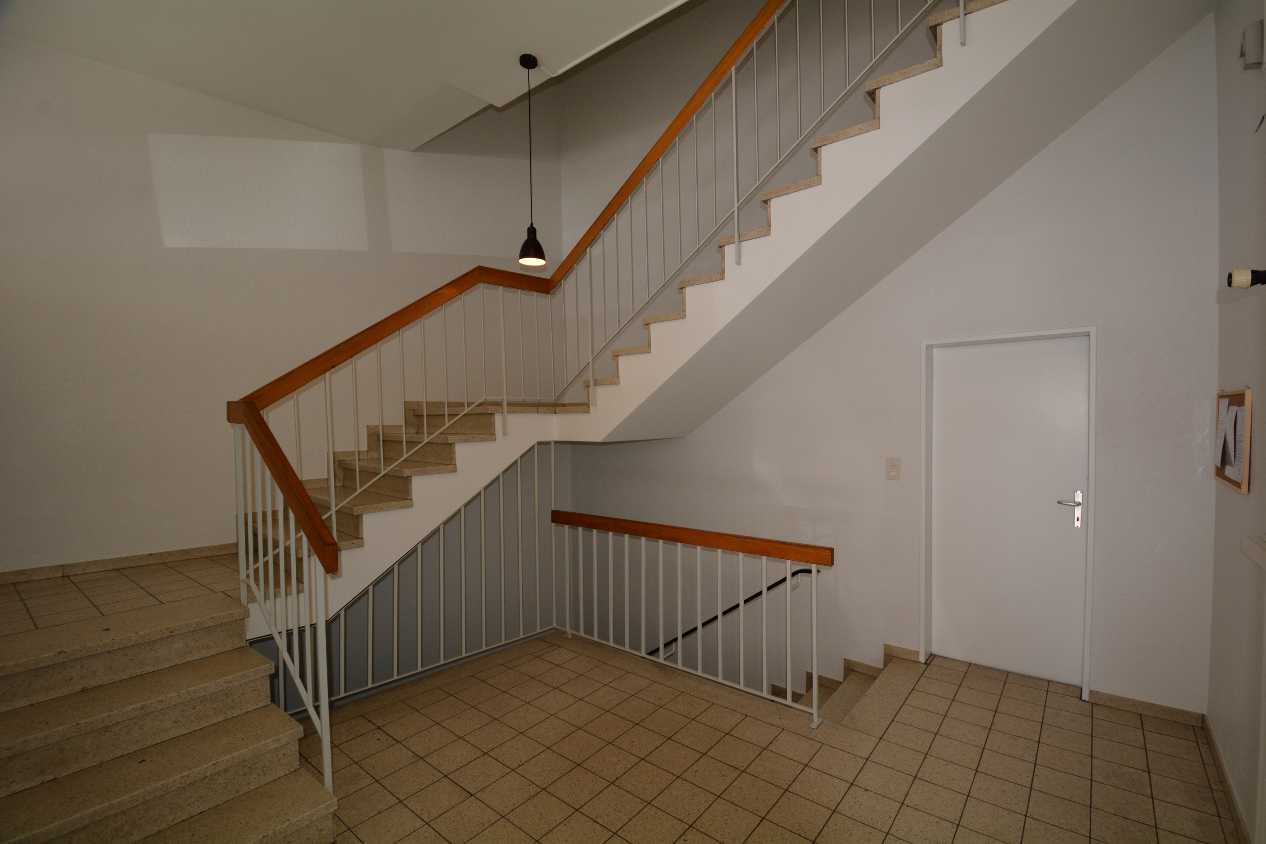a stairwell leads to an empty room with a white door
