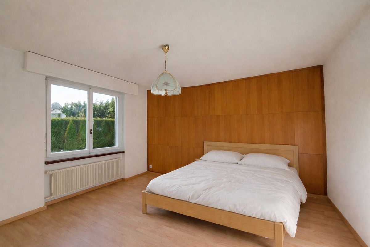 Chambre avec lit double et parquet au sol.