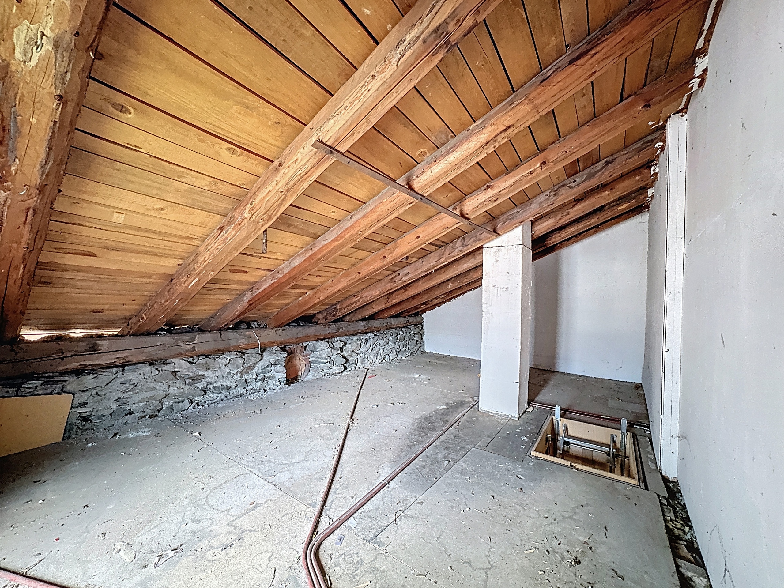 le grenier d'une vieille maison avec des murs et un plafond en bois