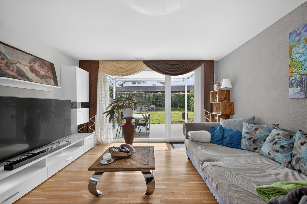 Helles Wohnzimmer mit Zugang zum Garten über grosse Glastüren.
