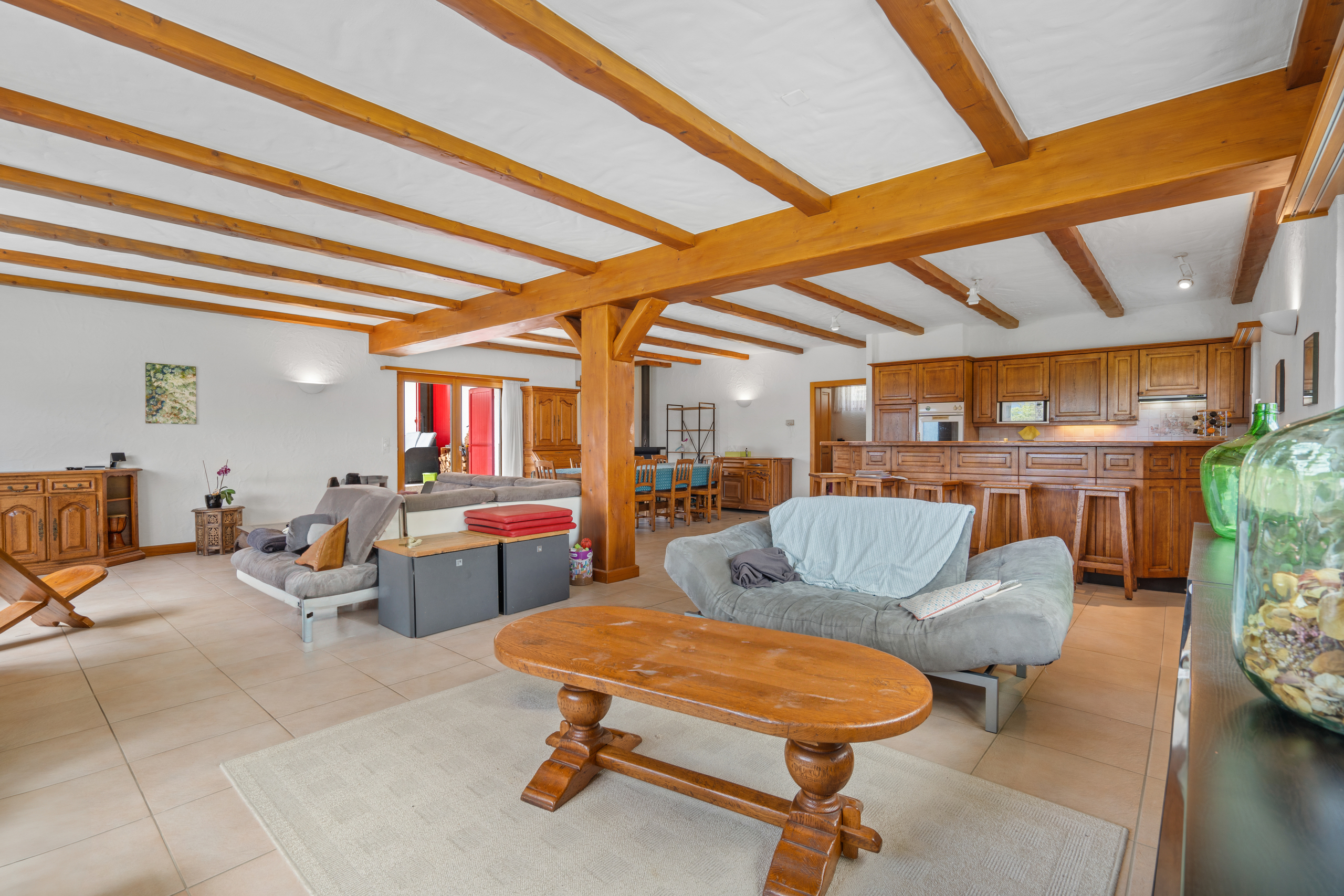 une grande pièce avec des poutres en bois, un canapé, une table et des chaises une grande pièce avec des poutres en bois, un canapé, une table et des chaises