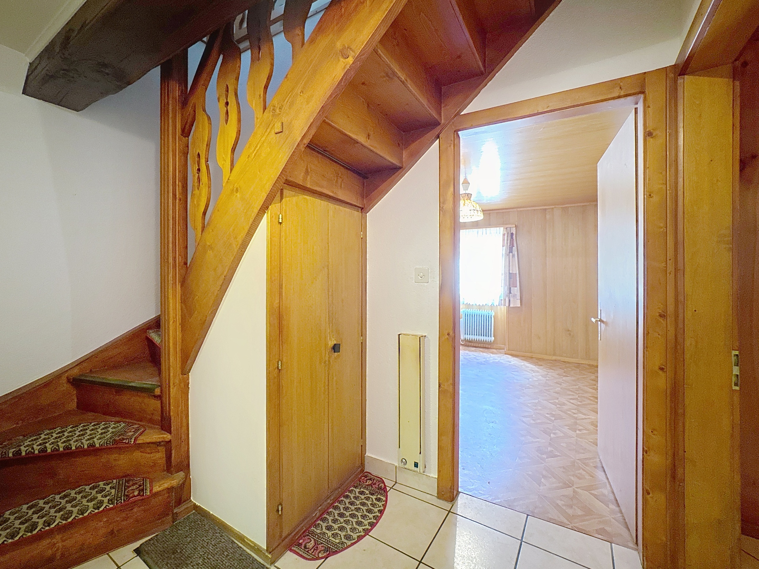 un couloir avec des escaliers en bois menant à une porte menant à une autre pièce au deuxième étage