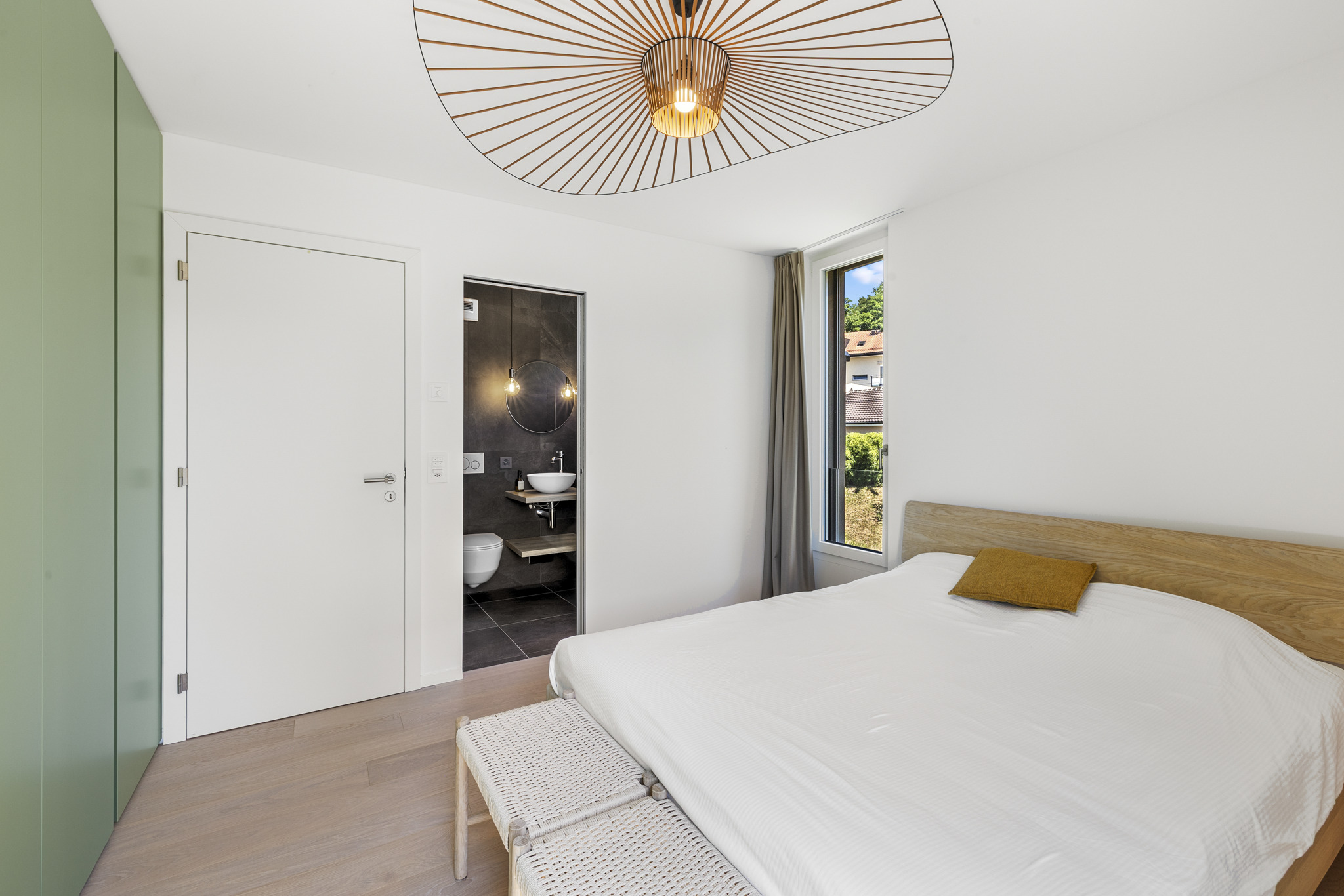 a modern bedroom with a white bed, a large window, and a door that leads to the bathroom a modern bedroom with a white bed, a large window, and a door that leads to the bathroom