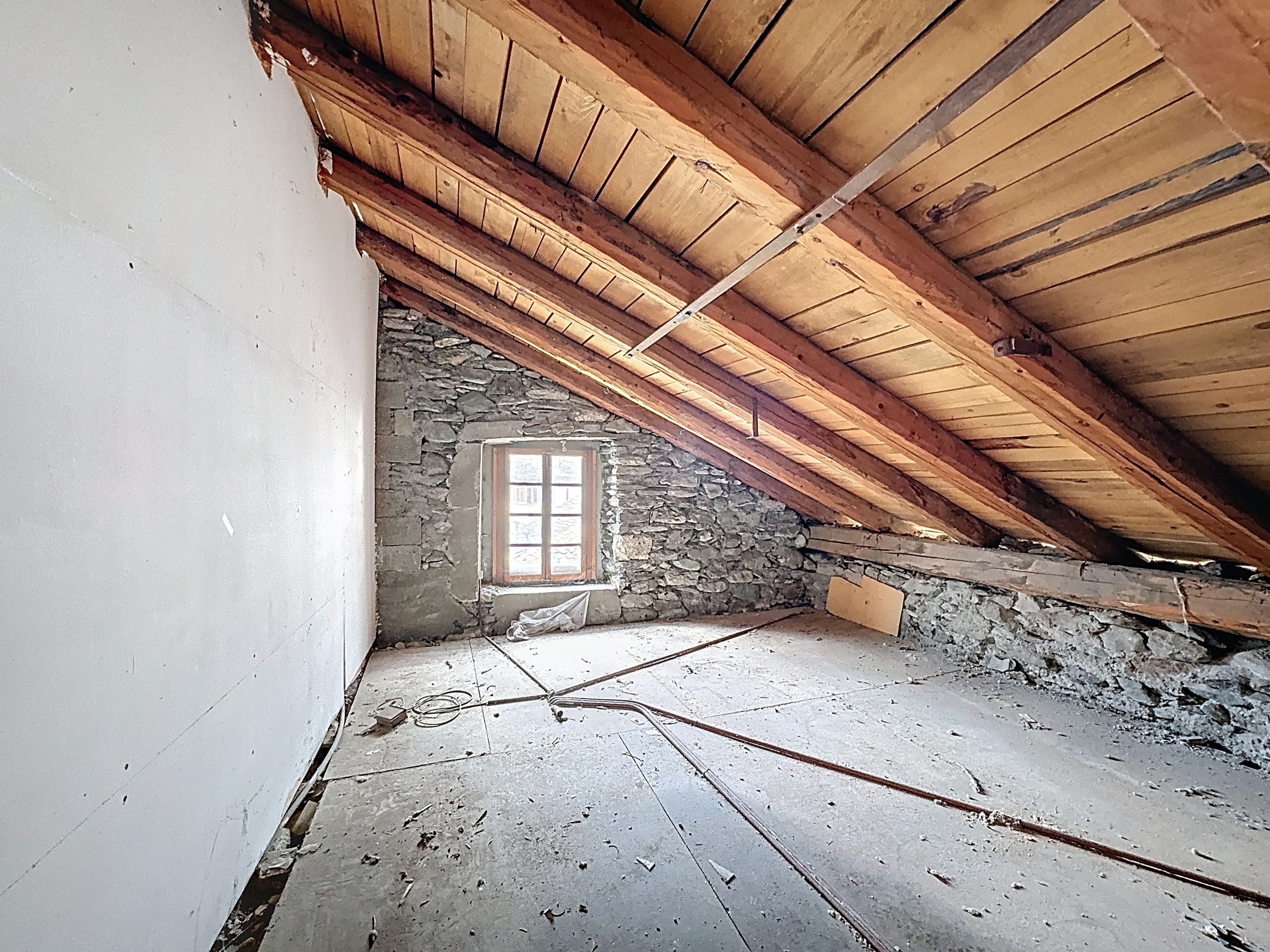 le grenier d'une vieille maison avec un plafond voûté et une fenêtre à l'étage