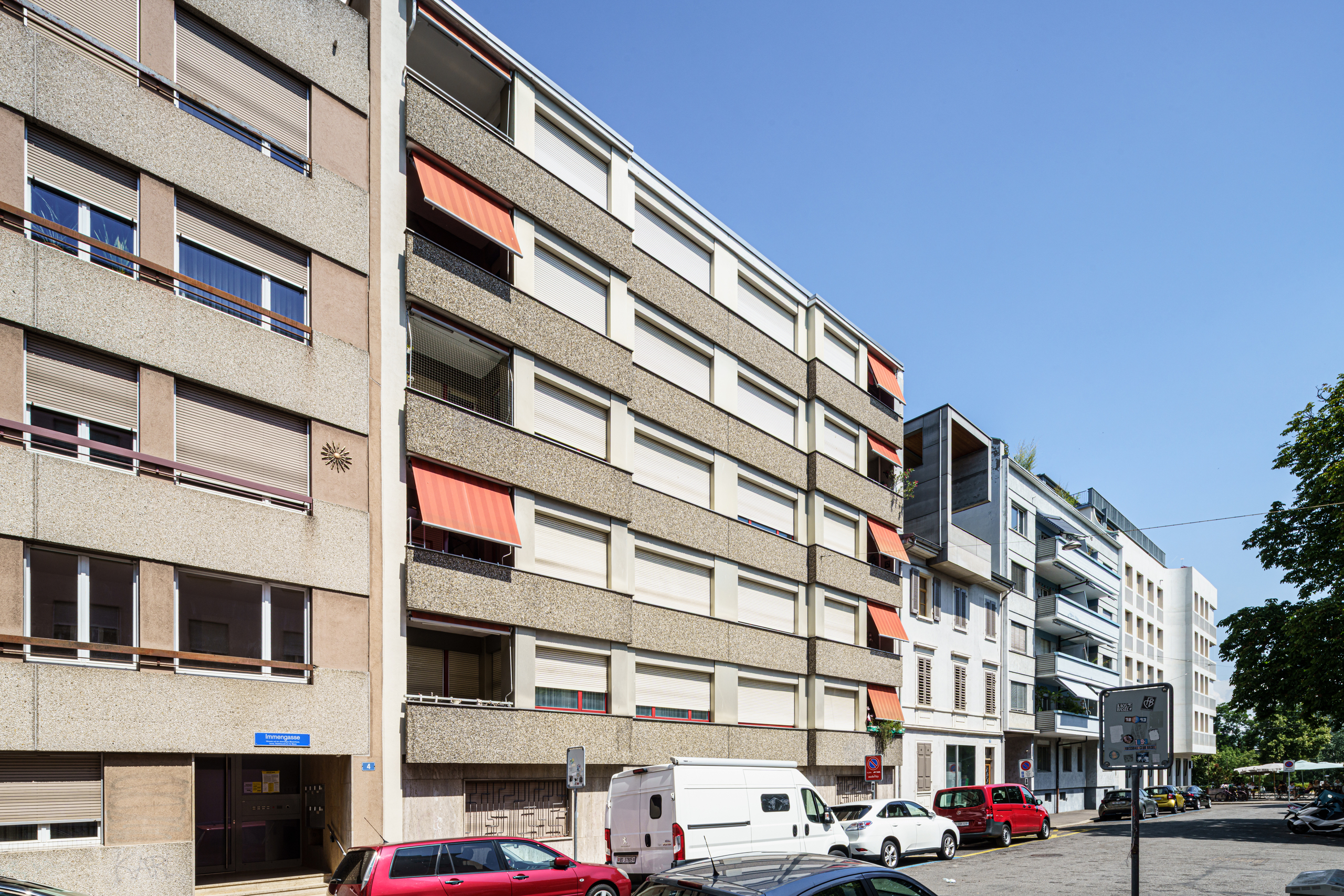 Autos, die auf einem Parkplatz vor einem Wohnhaus stehen Autos, die auf einem Parkplatz vor einem Wohnhaus stehen