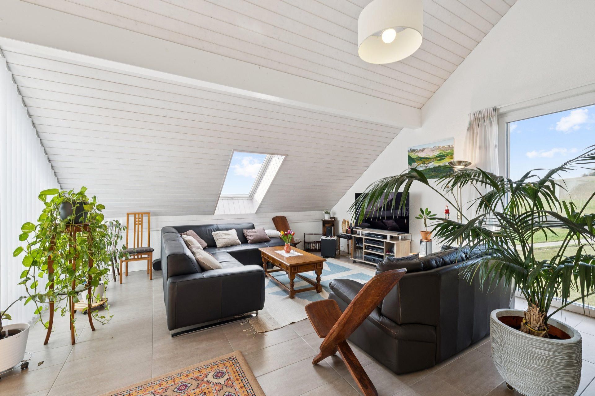 un salon avec un plafond voûté, de grandes fenêtres et des plantes en pot