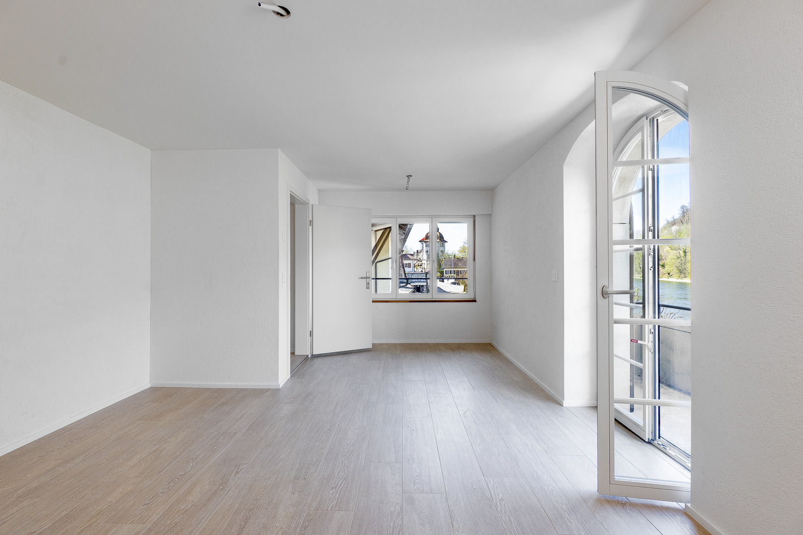 ein leerer Raum mit weißen Wänden und Holzböden und einem großen Fenster