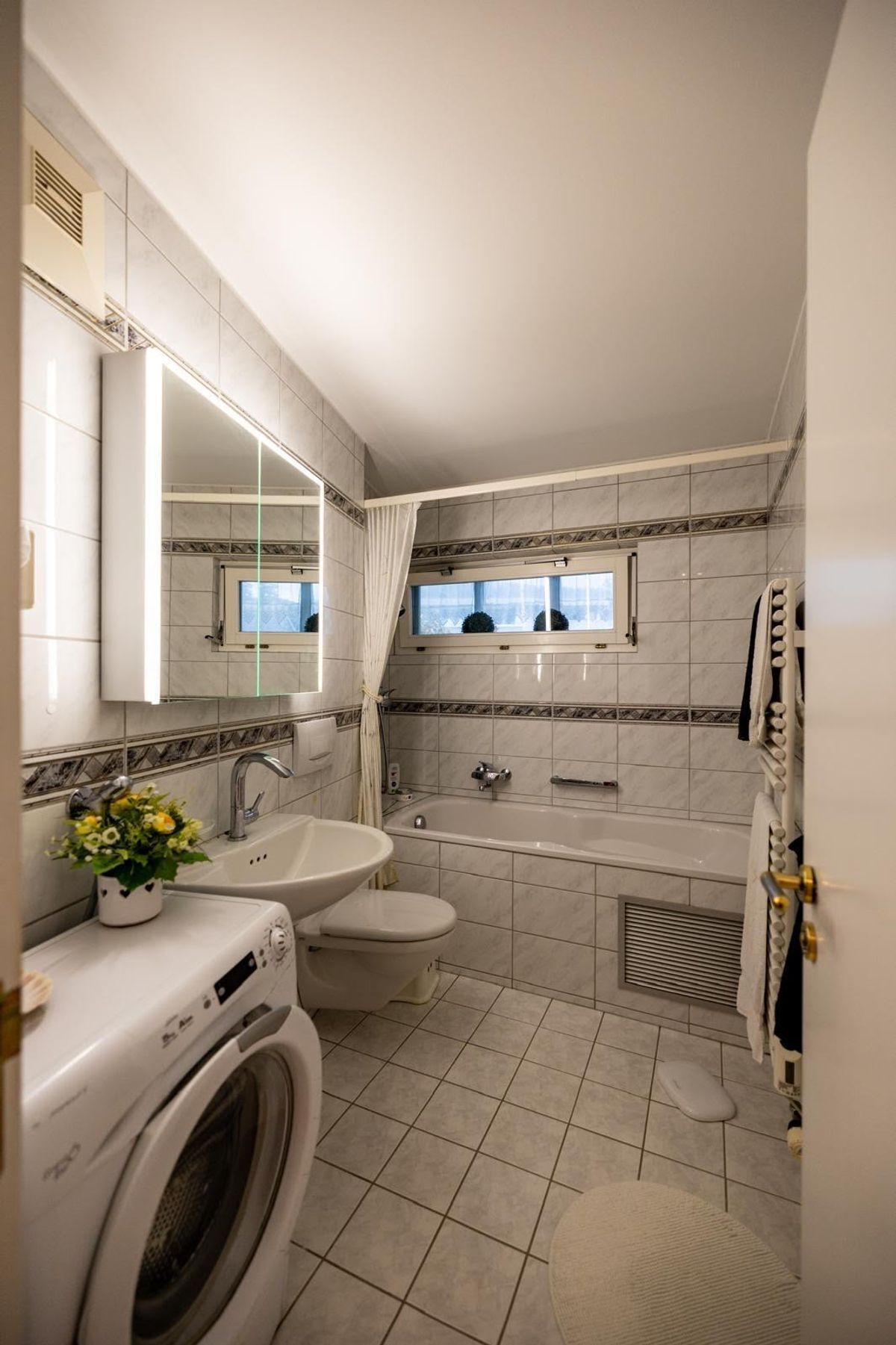 Gut ausgestattetes Badezimmer mit Waschmaschine, Dusche und Badewanne.