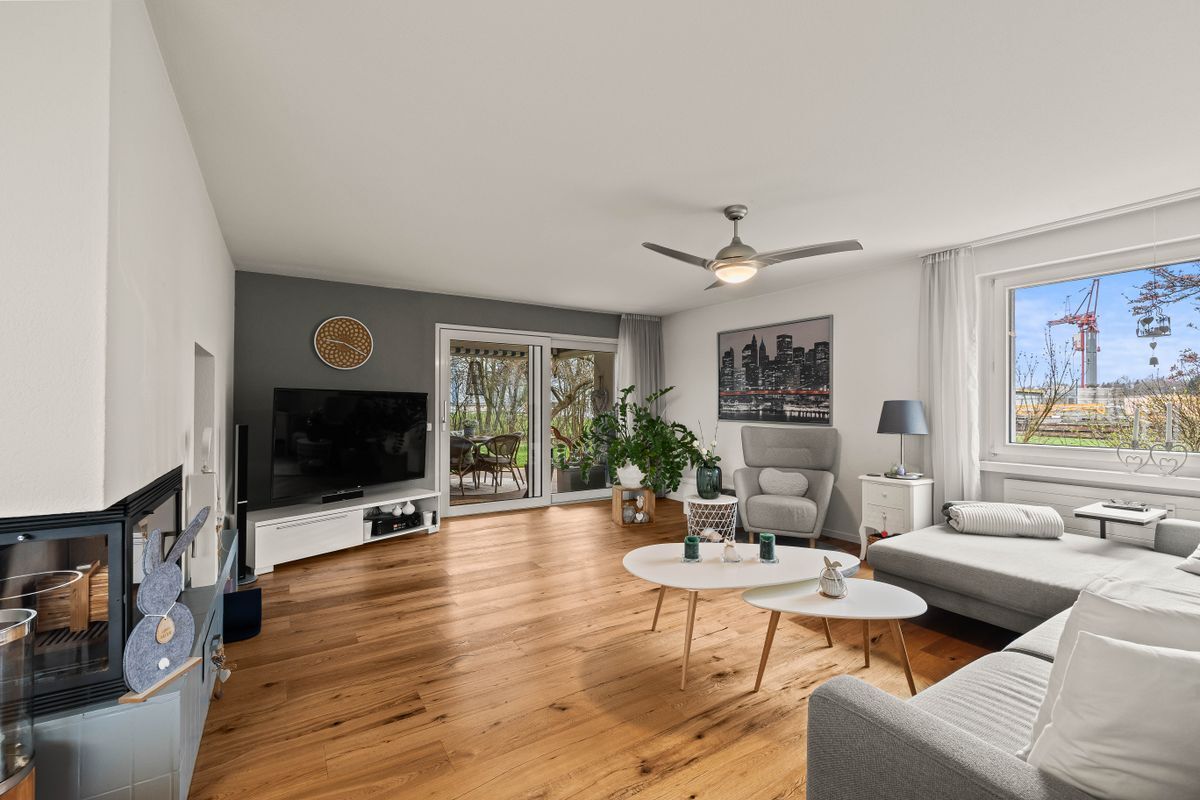 Helles Wohnzimmer mit großem Fenster und Zugang zur Terrasse.