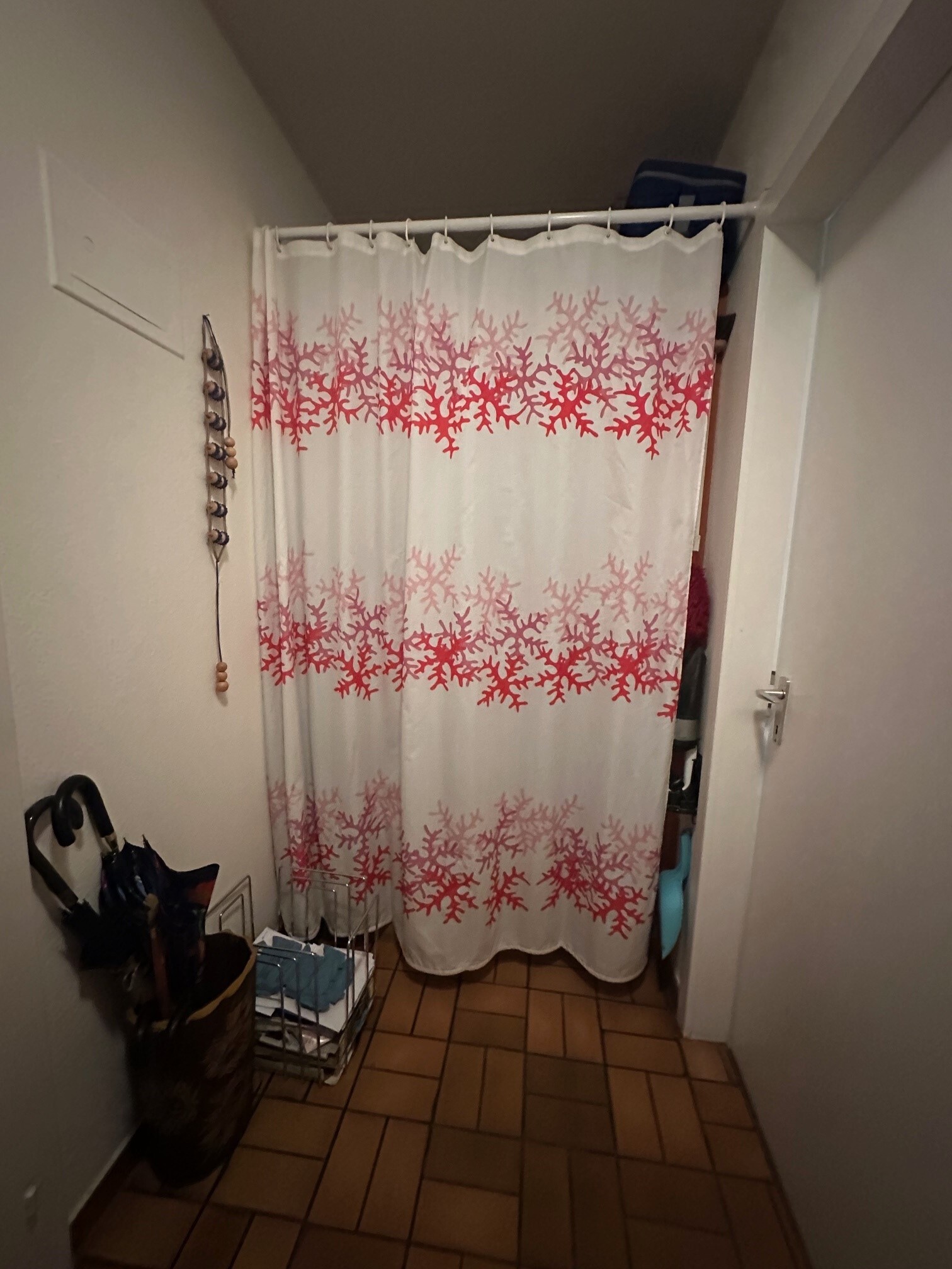 a small bathroom with a white shower and red shower curtain