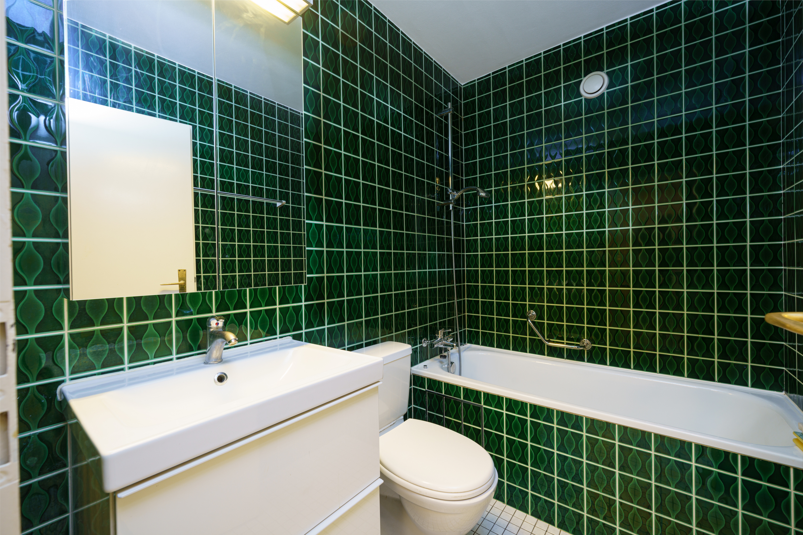 ein Badezimmer mit grünen Fliesen an den Wänden und einem weißen Waschbecken und einer weißen Badewanne ein Badezimmer mit grünen Fliesen an den Wänden und einem weißen Waschbecken und einer weißen Badewanne