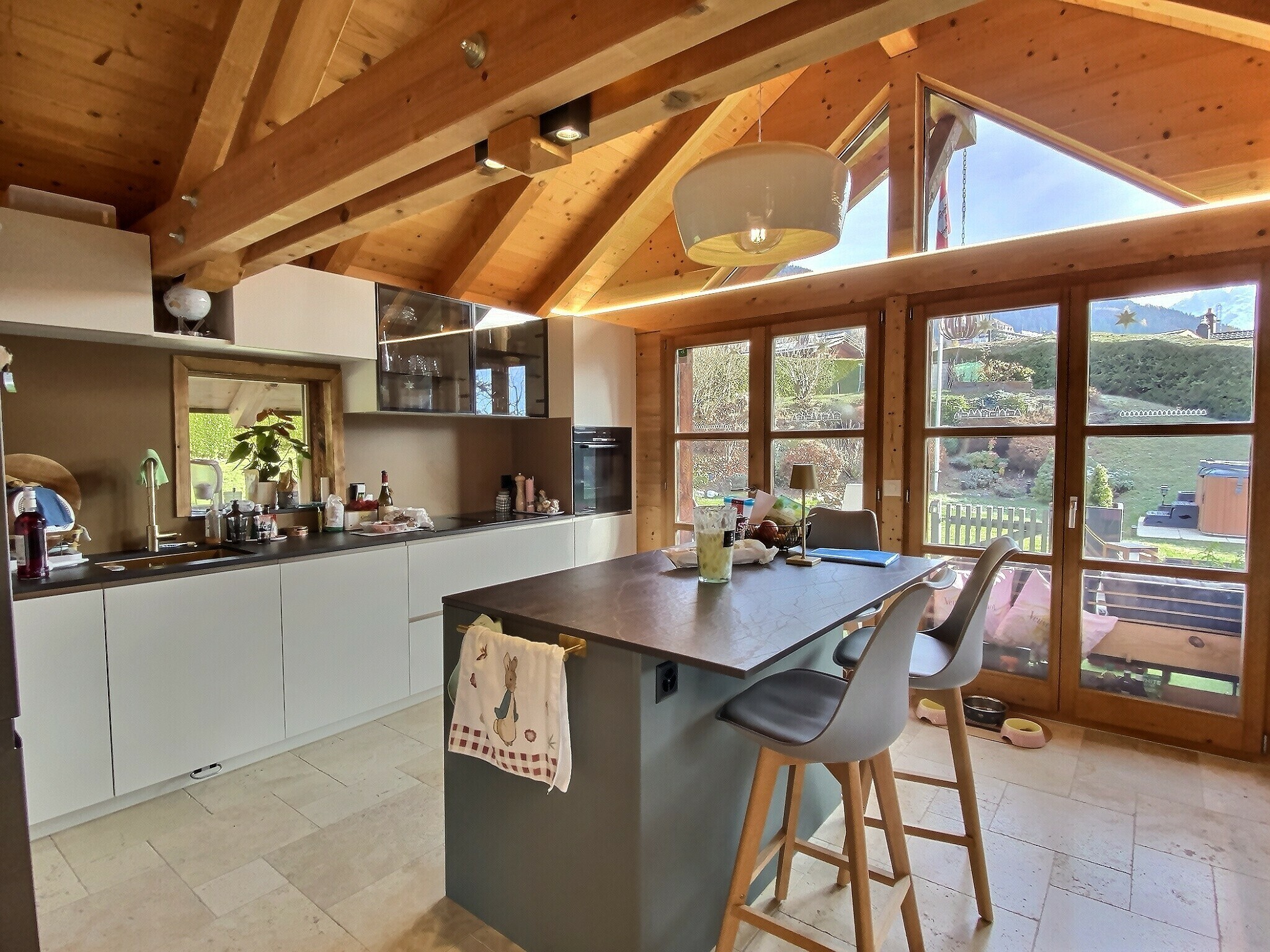 une cuisine moderne avec des plafonds en bois et de grandes fenêtres