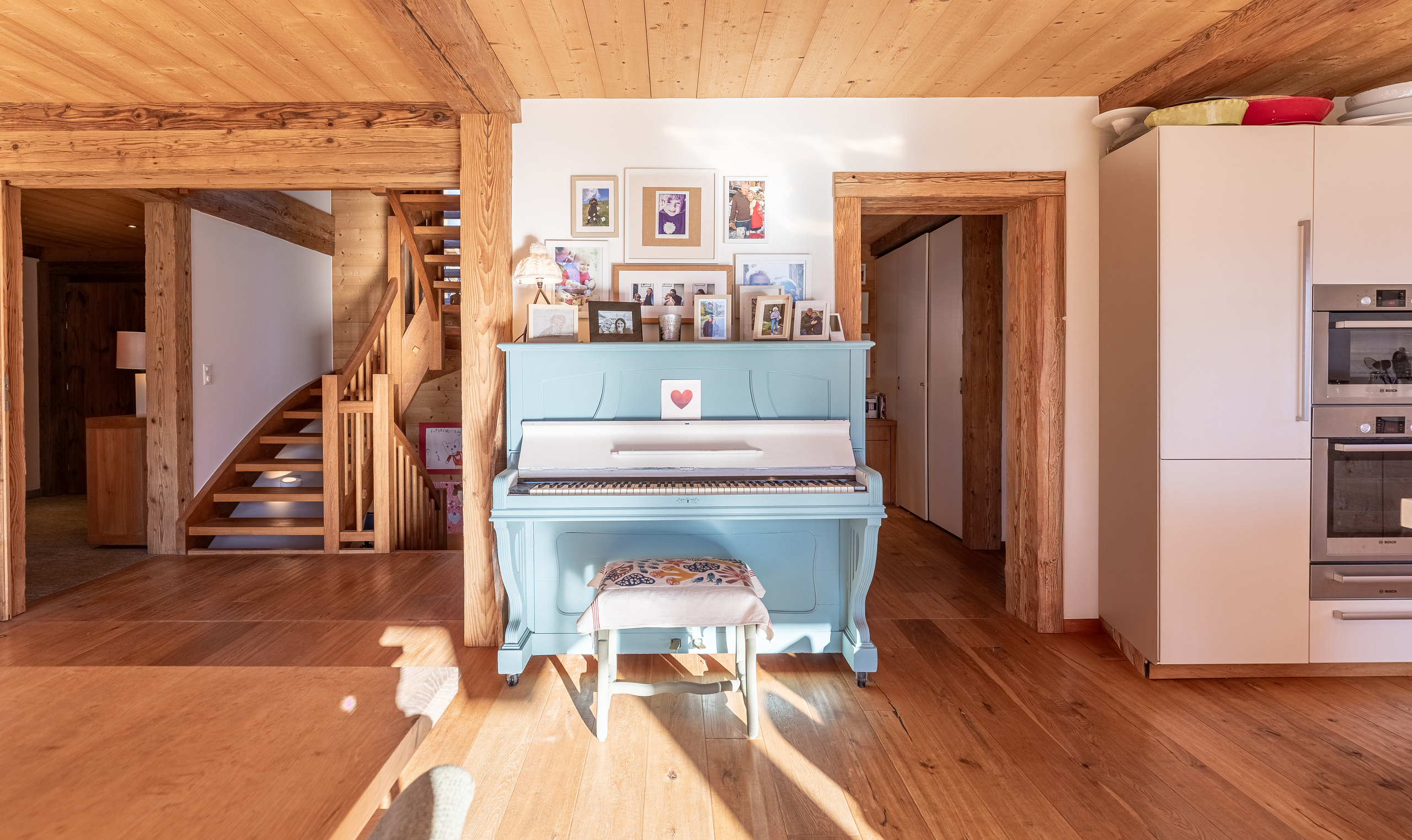 un piano bleu et blanc dans une pièce au sol et à l'escalier en bois