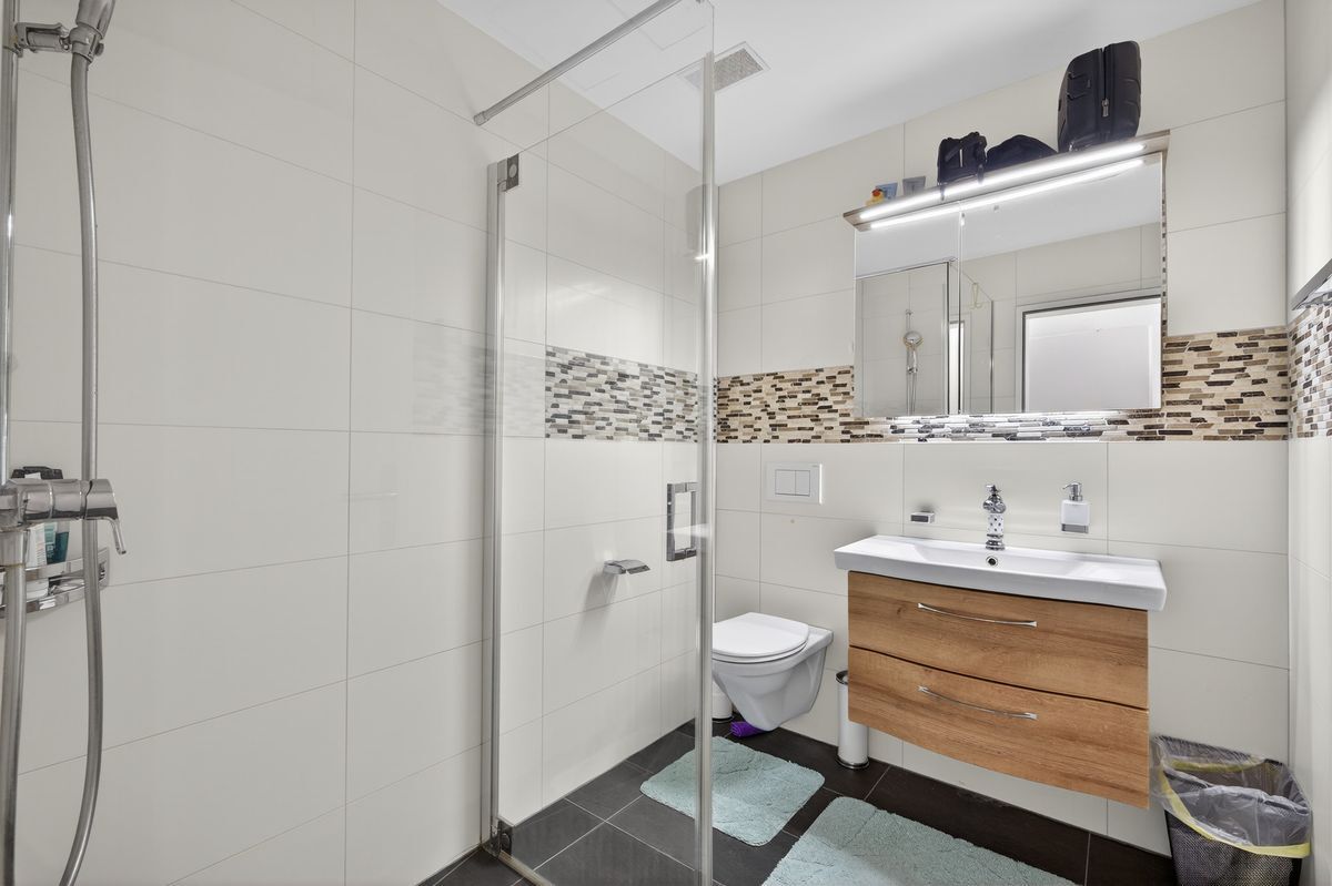 Modernes Duschbad mit grosser Dusche, WC und praktischer Waschtischanlage.