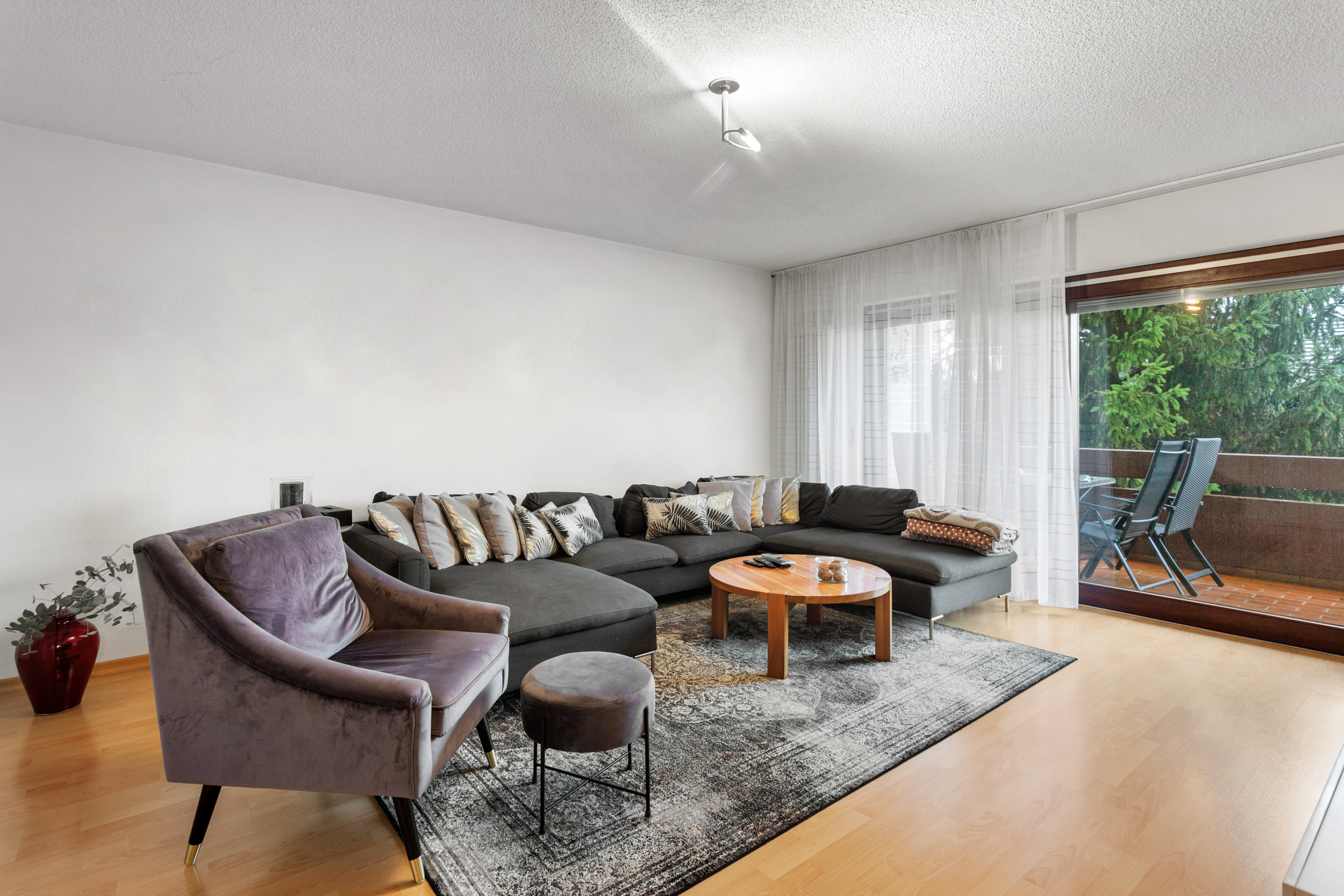 Das helle Wohnzimmer mit direkten Zugang zum überdachten Balkon mit schöner Aussicht.