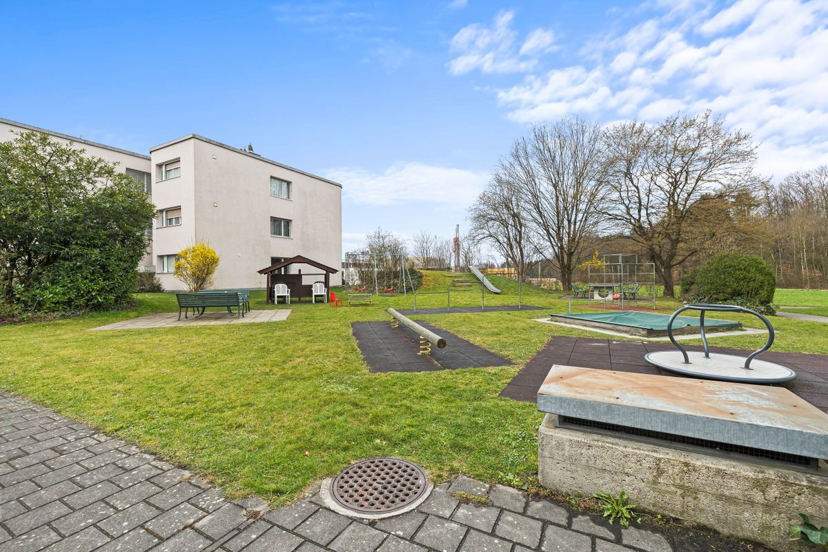 Außenbereich mit Spielplatz neben Wohngebäude.