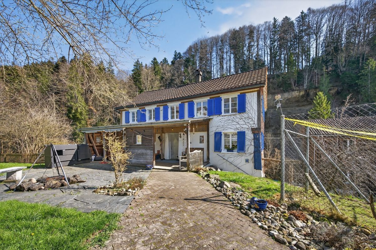 Traditionale Fassade mit blauen Fensterläden und Gartenansicht.
