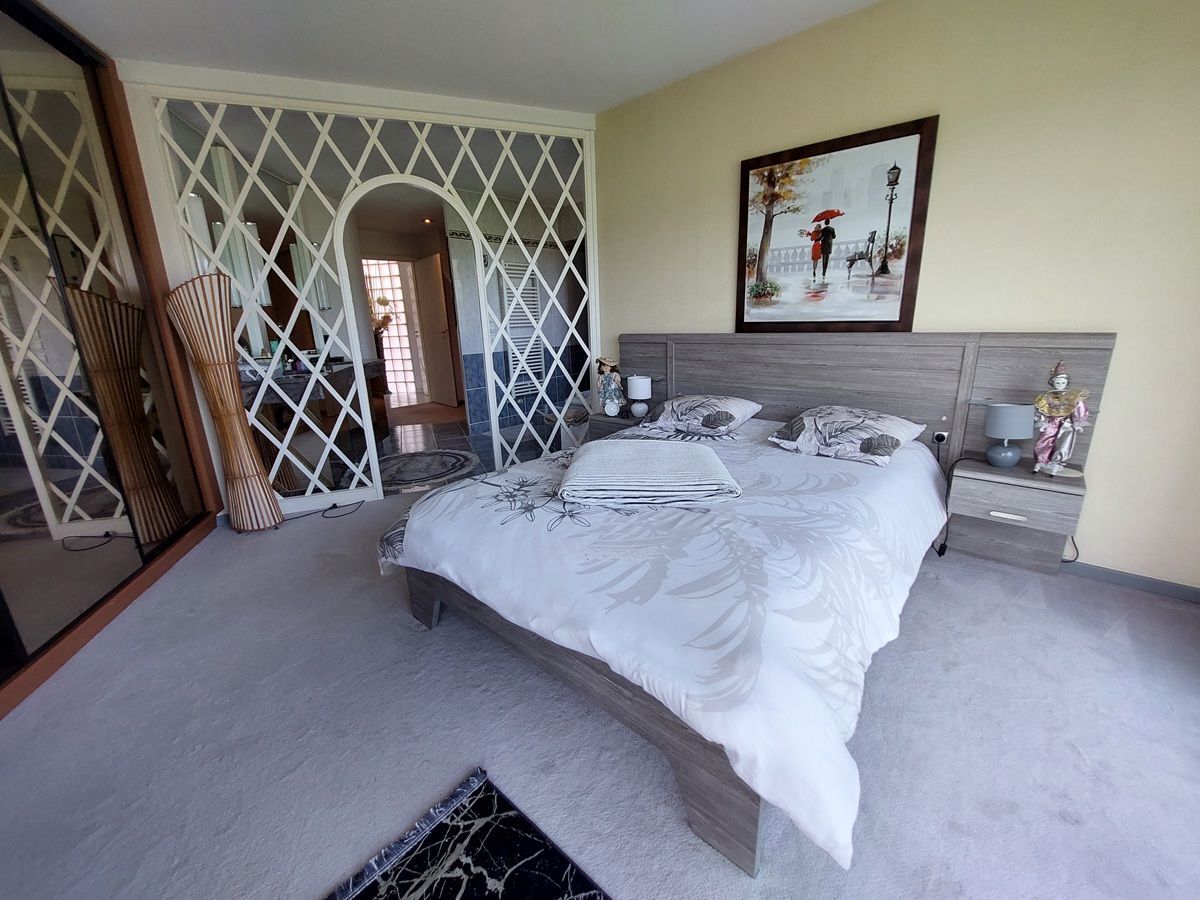 Chambre avec grand lit et oeuvre d'art au mur.