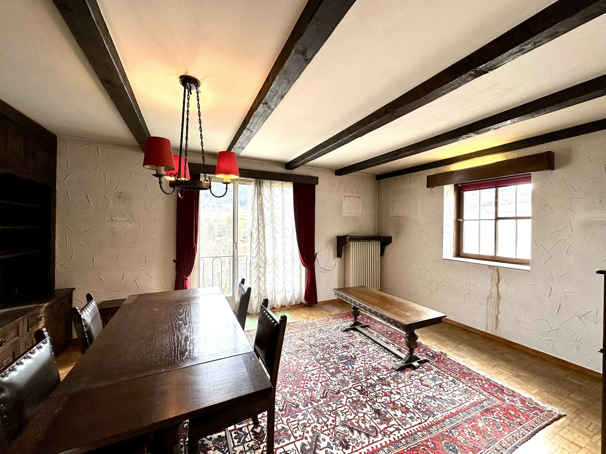 une pièce avec un plafond voûté, une grande fenêtre et une table en bois avec un banc une pièce avec un plafond voûté, une grande fenêtre et une table en bois avec un banc